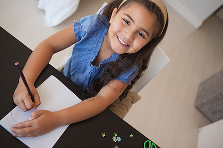 一个微笑的年轻女孩在桌子上画画的肖像背景图片
