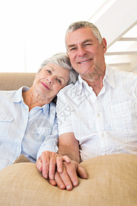 持手在沙发上笑着看镜头的退休夫妇图片