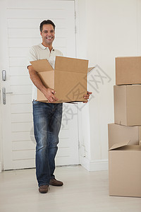 微笑者在新房子里携带箱子房地产男性棕色快乐男人开箱纸盒闲暇包装公寓图片
