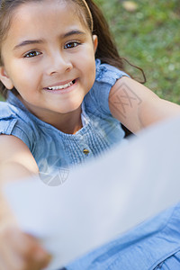 微笑的姑娘在公园里拿着一纸模糊的纸背景图片