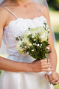 公园中带花束的美丽新娘的中间部分图片