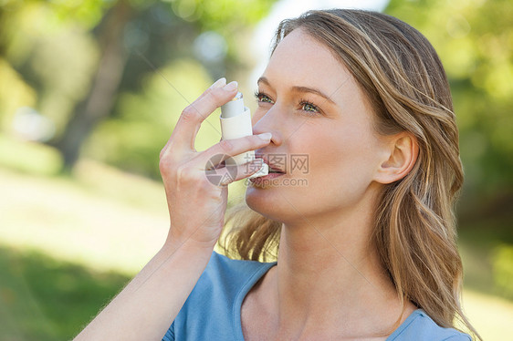 在公园使用哮喘吸入器的妇女金发女郎头发闲暇女性浅色女士金发卫生疾病哮喘病图片