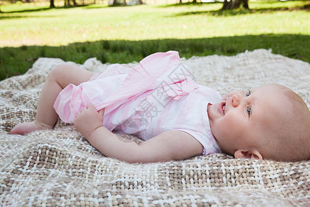坐在公园毯子上的可爱婴儿的侧面视图图片