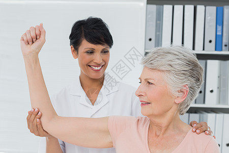 帮助高龄妇女伸手的妇产科治疗师按摩混血成人身体检查双手医生医院女性人员图片