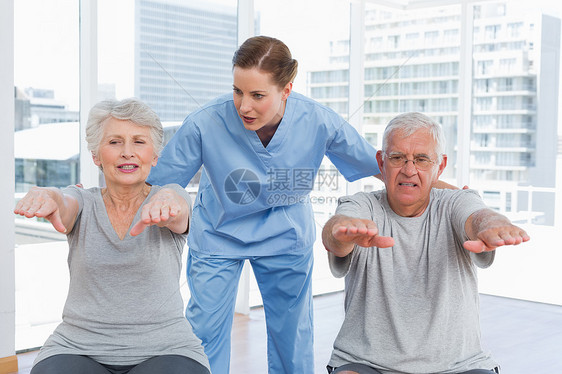 女性治疗师协助老年夫妇锻炼的女性治疗师健身房医院理疗病人制服帮助医生退休康复治愈图片