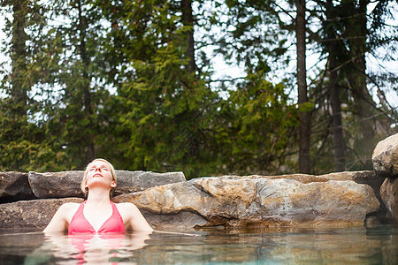 在北欧斯帕放松的年轻女性游客比基尼旅行金发女郎享受温泉水疗水池蒸汽地热图片