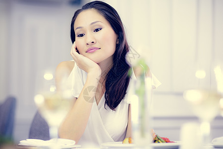 吃饭桌边的有思想的美丽的女人食物桌子思维玻璃沙拉棕色女性女士头发白酒图片