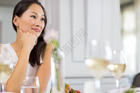 吃饭桌边的有思想的美丽的女人桌子女性酒杯棕色玻璃食物白酒思维女士酒精图片