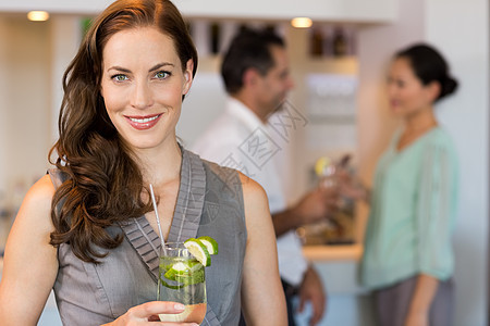 微笑的女人拿着鸡尾酒杯 和朋友在酒吧图片