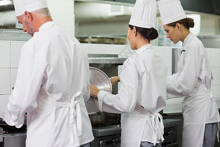 在炉灶工作的一排厨师烹饪女士合作同事商业男人酒店专注餐厅职员图片