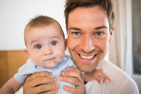 父亲和儿子坐在床上 在蓝色的婴儿园里幸福男性卧室快乐房子婴儿棉被家庭感情服装图片