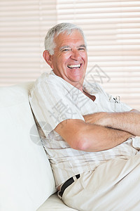 坐在沙发上快乐的高级男子双臂老年成人头发男人住所退休房子客厅公寓图片