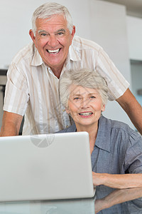 快乐的老年情侣 在餐桌上使用笔记本电脑公寓女性女士夫妻倾斜住所家庭微笑男人桌子图片