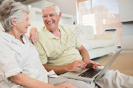 用笔记本电脑一起坐在地毯上 幸福的老年夫妇退休房子公寓女士成人闲暇头发男性小地毯微笑图片