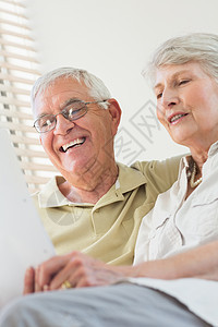 在沙发上一起看文件的年长夫妇微笑男性女士老年男人闲暇成人长椅夫妻房子图片