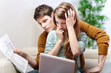 焦虑的年轻夫妇咨询他们的银行户头女孩恋人悲伤互联网沙发电脑男生痛苦夫妻长椅图片