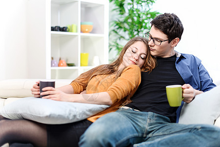 在客厅沙发上一起放松的一对幸福快乐的情侣女孩女性场景杯子男生男性房子福利恋人咖啡图片