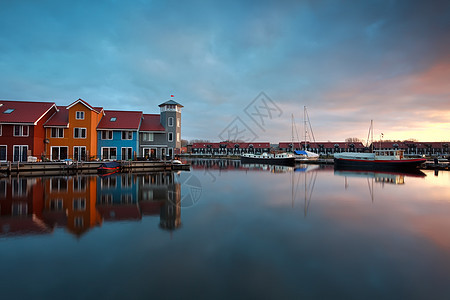 日出时在码头上 有建筑物和船只图片