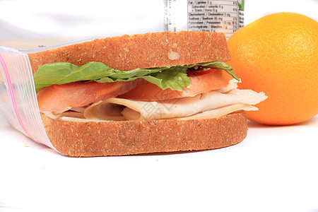 夹在拉链塑料午餐袋中的三明治水果小吃面包果汁营养白色压缩蔬菜食物橙子图片