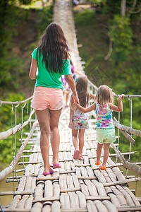 年轻母亲和她的小女儿在菲律宾罗博河悬索桥上的背影图片