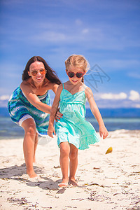 女孩和年轻母亲在沙漠岛屿热带海滩上玩得开心图片