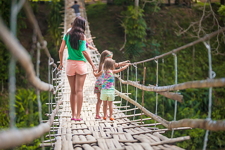 在菲律宾洛博克河上悬吊桥上行走的小女孩和年轻女子背视镜女士女孩女儿小路女性危险溪流风险叶子人行道图片