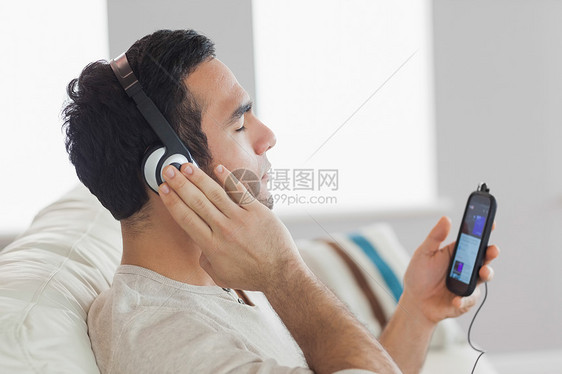 听音乐的英俊帅哥手机享受男人耳机微笑眼睛房子沙发头发公寓图片