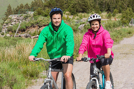 骑自行车的快乐情侣穿着戴头罩的跳跃者图片