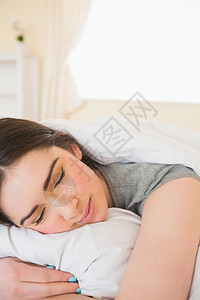微笑的女孩睡在床上软垫公寓女性闲暇棕色快乐睡衣房子羽绒被午睡图片