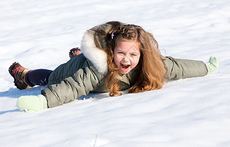 女孩在雪中躺下孩子乐趣快乐公园场地季节帽子女性衣服夹克图片
