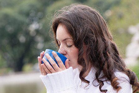 女青年在户外喝热茶的肖像毛衣杯子夹克楷模头发蓝色皮肤手指肤色女性图片