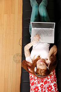 年轻的红发女孩在沙发上冲浪女孩青年电脑成人休息耳机女性地面展示青少年图片