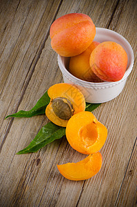 木桌上的杏子甜点水果桌子种子木板白色橙子黄色植物叶子图片