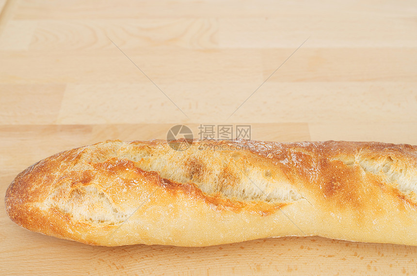 木制切割板上的法国面包包酵母面包木头硬皮脆皮面粉营养小麦乡村食物图片