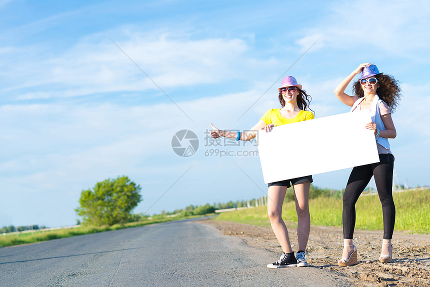 两名年轻女性站在空白的横幅上站着女士季节女孩旅行假期航程远足者游客冒险便车图片