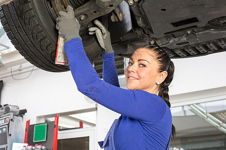 在液压坡道修理一辆汽车的机械机修理工职业工人车库工程师检查女性工具服务作坊图片