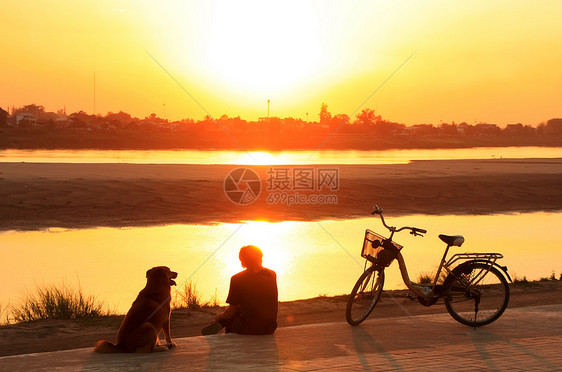 在湄公河水边看日落时 带狗的地标纪念碑文化景观自行车日出首都国家剪影橙子图片