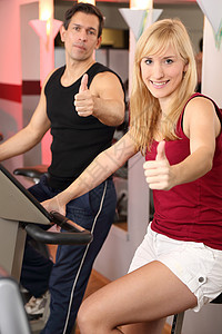迷人的女人和男人在健身房骑自行车健身有氧运动运动机身体家庭教练成年人运动服机器培训师训练图片