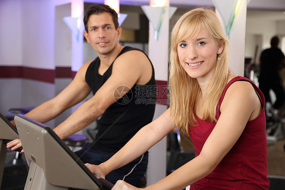 迷人的女人和男人在健身房骑自行车培训师机器运动服火车训练女士运动运动装有氧运动健身图片