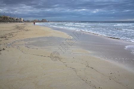 海滩上带着橄榄球走路的男人图片