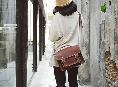 在混凝土小巷带皮包的时装女孩皮革衣服旅行帆布女士魅力女性奢华手提包街道图片