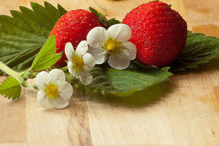草莓在树叶上 前景下有花朵图片