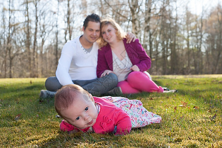 在草地上的女孩 父母背景的婴儿女孩图片