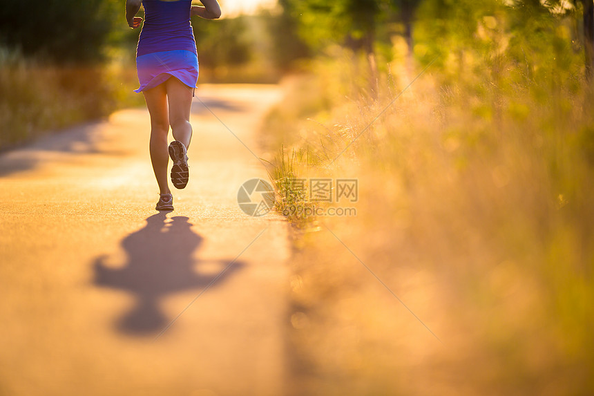 年轻女子在阳光明媚的夏日夜晚户外奔跑火车青年运动员慢跑者跑步草地城市寒冷女性闲暇图片