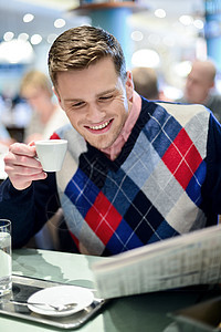 在户外咖啡厅看报纸的时尚男子图片