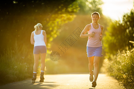 年轻女子在阳光明媚的夏日夜晚户外奔跑越野慢跑者火车公园女士闲暇背景女性城市慢跑图片