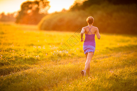 年轻女子在阳光明媚的夏日夜晚户外奔跑运动员闲暇女士赛跑者公园城市背景跑步娱乐运动装图片