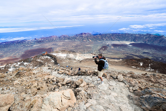 男人在顶层火山上拍照片 在山顶的双面水平图片