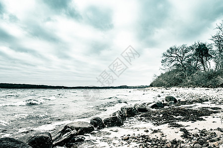 寒冷的一天 海浪在岸边的大黑岩石上涌来图片