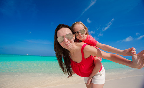年轻美丽的母亲和可爱的女儿 在热带沙滩玩得开心极了图片